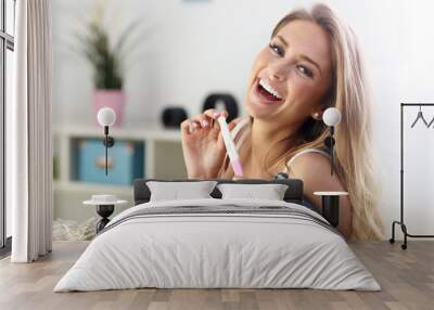 Happy woman with pregnancy test at home Wall mural