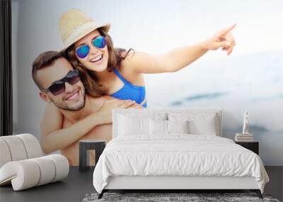 young couple pointing at something at the beach Wall mural