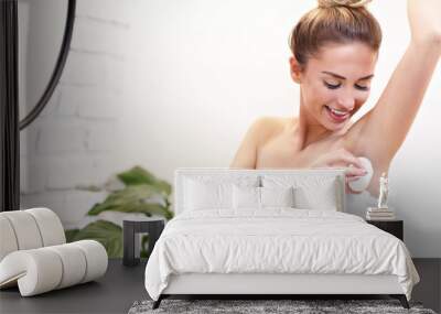 Young woman using deodorant in bathroom Wall mural