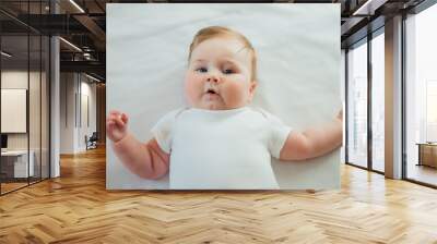 Cute infant baby lying on white sheets Wall mural