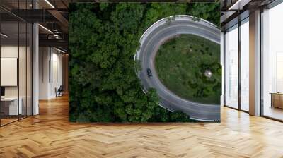 Aerial view car drive in green tree forest road winding road through the forest, Car drive on asphalt road between green tree forest, Electric vehicle EV car drive on asphalt road green tree forest. Wall mural