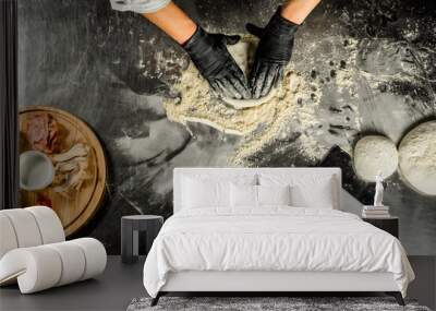 dough, flour, pizza topping, sauce and chef's hands in black gloves on the table Wall mural