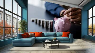 A businessman holding a coin in a piggy bank. Placing coins in a row from low to high is comparable to saving money to grow more. The concept of growing savings and saving by investing in stock funds. Wall mural