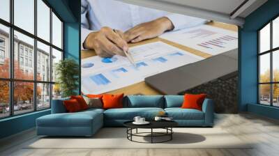 A businessman is reading a monthly sales graph in his office. He checks the sales volume of each salesperson to summarize the commission. Sales management concept. Wall mural