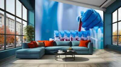 Lab assistant, a medical scientist, a chemistry researcher holds a glass tube through the blood sample, does a chemical experiment and examines a patient's blood sample. Medicine and research concept. Wall mural