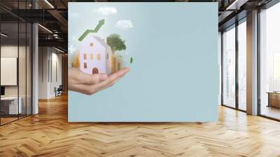 Real estate business investment and technology. Hand holding paper house with stack of bitcoin or gold coin and raising graph.Business investment and loans for real estate concept. Wall mural