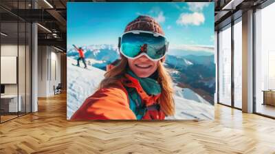 A woman snowboarder taking a selfie on top of a mountain, capturing the panoramic vista behind her  Wall mural