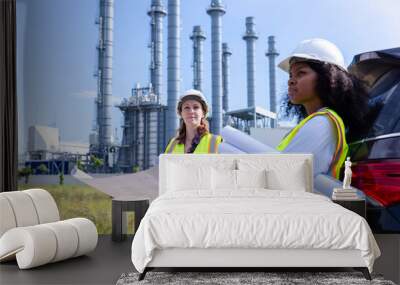 Female Engineers Holding Blueprints and Conducting Site Survey at Industrial Plant, Wearing Safety Vests and Helmets, Standing Near Equipment and Towers Wall mural