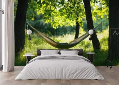 A serene hammock suspended between two trees, inviting relaxation in a lush green forest setting under soft sunlight. Wall mural