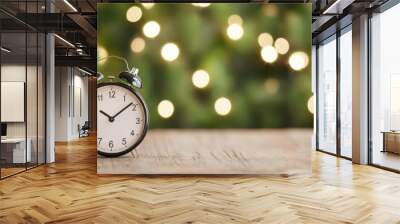 Vintage alarm clock on wooden table with blurred festive lights in background. Wall mural