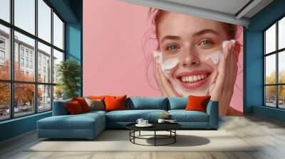 Young beautiful smiling woman washing her face with foam cleanser Wall mural