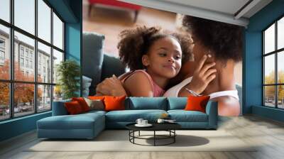 Loving African American mother and daughter hugging. Woman and girl in casual clothes holding each other on coach. Love, family, bonding concept Wall mural