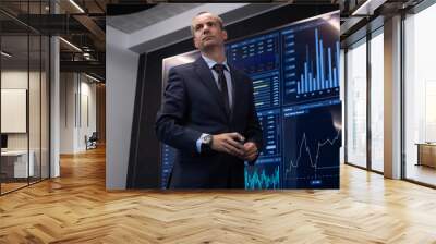 Portrait of businessman making financial analytics. Low angle view of serious man analyzing data of stock market for purpose of investment. Business growth and investment activity concept Wall mural