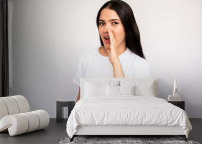 Portrait of young woman whispering secret covering mouth with hand over white background. Caucasian lady wearing white T-shirt telling gossip. Secret and gossip concept Wall mural