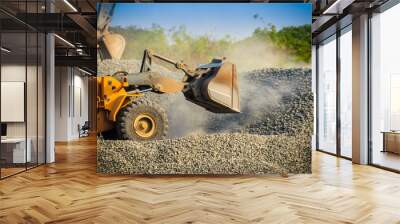 Yellow wheel loader bulldozer is working in quarry against the background of crushed stone storage. Wall mural