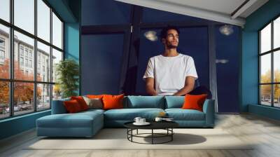 African American man in a white T-shirt sitting on a window. Mock-up. Wall mural