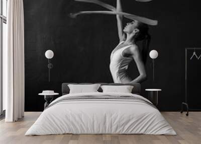 Beautiful woman gymnast with a white ribbon on a black background. Wall mural