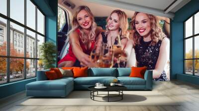 Pretty women having party in a limousine car and drinking champagne. Wall mural