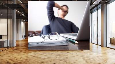 man with his hand holding his face taking a brake from working with laptop computer and notebook wit Wall mural