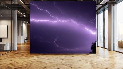 Lightning at night Which causes a white beam of light Contrast purple sky Wall mural