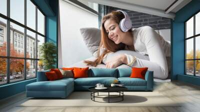 Asian woman relax on sofa bed, She listening to music from headphones. Wall mural