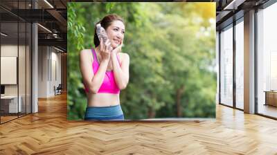 Young asian woman relaxing in the park, Holding water bottle in hand. Wall mural