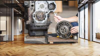 Mechanic man holding front Gear of diesel commonrail engine in heavy machinery workshop Wall mural