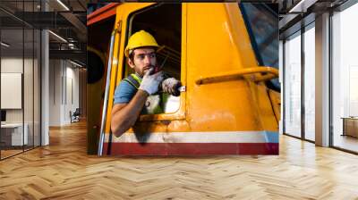 A handsome train driver uses a walkie-talkie or walkie-talkie in the interior room to control the train. Professional railway engineer. Wall mural