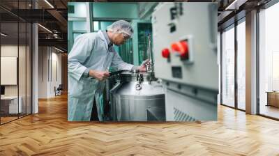 A man in a white lab coat is working on a machine. The machine is large and has a red button on it Wall mural