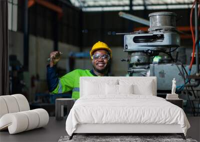 Portrait of an African American engineer standing with his arms crossed, inspecting and controlling an automated welding robot. The robotic arm in the automotive factory is smart. Wall mural