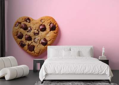 A heart-shaped chocolate chip cookie on a pink background. Wall mural