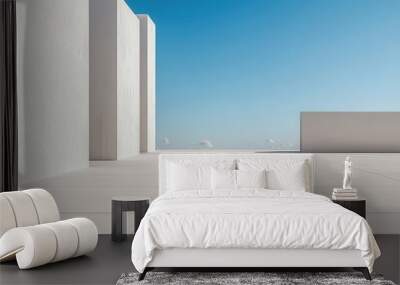 A minimalist outdoor space featuring white walls and a clear blue sky, offering a serene and modern aesthetic. Wall mural