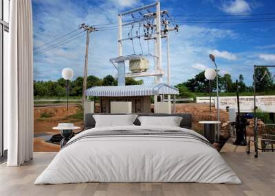 Outdoor sewage treatment station. Pump control cabinet with high voltage transformer and cable on pole On the blue sky background with white clouds. Selective focus Wall mural