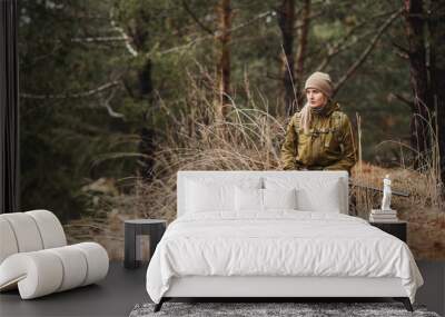 Female hunter in camouflage clothes ready to hunt, holding gun and walking in forest. Wall mural