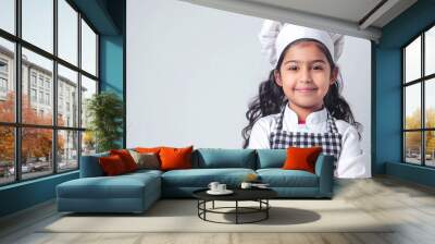 A cute happy smiling young Indian girl dresses like a chef on a plain white background with copy space for text. Wall mural