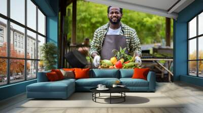 Farmer holding wooden box full of fresh  vegetables. Basket with vegetable. Man holding big box with different fresh farm vegetables. Wall mural