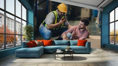 First aid support accident at work of worker at factory. Male worker has an accident on the floor in warehouse site. Wall mural