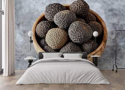 A wooden bowl filled with fresh black truffles on a textured surface. Wall mural