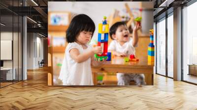 Asian boy and girl playing with colorful plastic blocks. Learning and imagination of young children. Hand muscle development. Toy sharing. Baby age 1 years and 2 years old. Wall mural