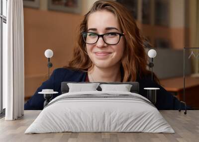 Close-up portrait of a young woman in glasses. A girl with red hair in the classroom. Business woman in training class Wall mural