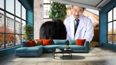 A Japanese doctor filling out a medical record while looking a patient in the eye and counseling him or her 1 Wall mural