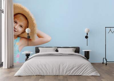 A young girl wearing a straw hat and a blue and pink swimsuit. She is smiling and looking at the camera. Banner with copy space. Wall mural