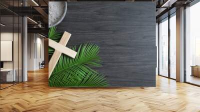 Border of small wood cross, palm leaves and bowl of ashes on a dark wood background with copy space Wall mural