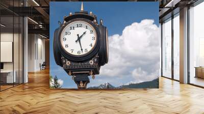 Old street clock over blue sky, clouds and mountain. Wall mural