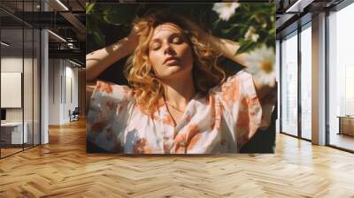 blond woman lies in the grass in the garden with closed eyes and has a rest Wall mural