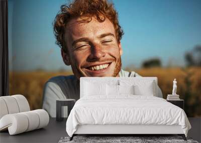 young man with red hair an freckles sitting in a field Wall mural