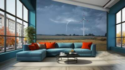 a lightning strikes the ground next to a wind turbine Wall mural