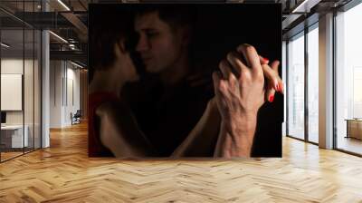 a man and a woman dancing tango in the dark; their hands are in focus and lit with the light Wall mural