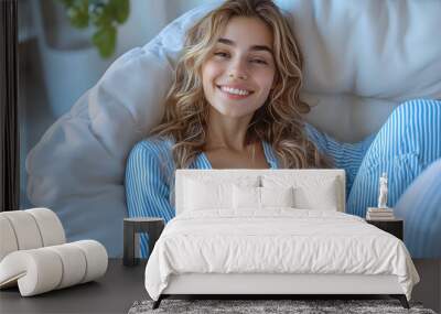 A cheerful woman in blue pajamas sitting comfortably and enjoying a bowl of fresh fruit, symbolizing healthy eating and a relaxed morning routine.
 Wall mural