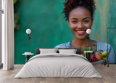 A happy woman holds a bowl of fresh produce, including fruits and vegetables, with a vibrant green wall in the background. Wall mural